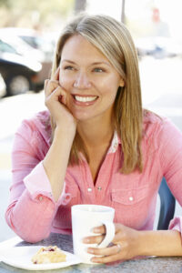 Picture of smiling woman sitting outside with a cup of coffee