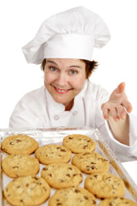 Picture of woman in a chef's hat holding a plate of cookies