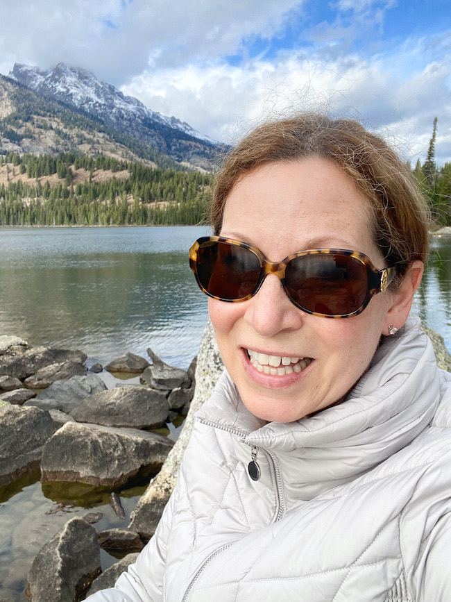 Picture of author Sara in front of water and the mountains.