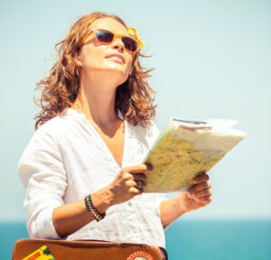Picture of woman looking forward holding a map and suitcase