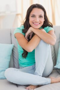 Picture of happy woman sitting on the floor looking at the camera